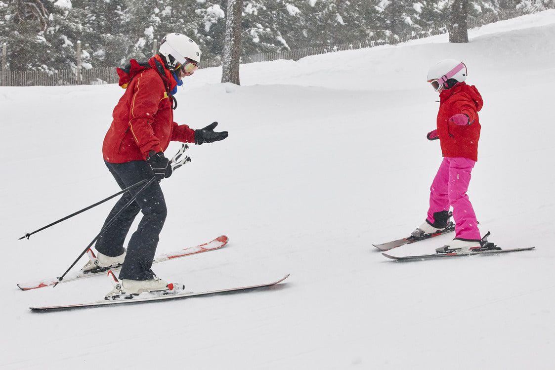 Kind lernt mit einem Lehrer Skifahren. Wintersport
