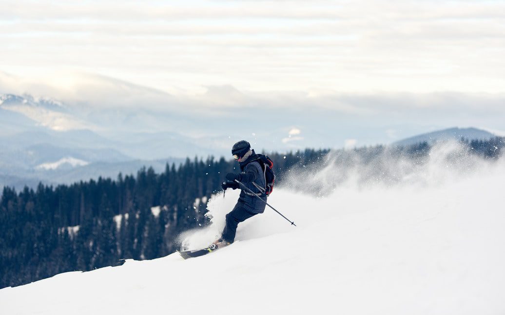 Mann fährt die Skipiste hinunter